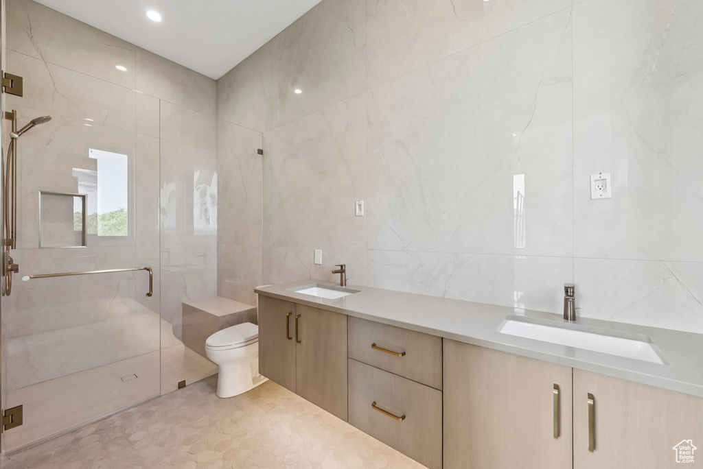 Bathroom with tile walls, a stall shower, and double vanity