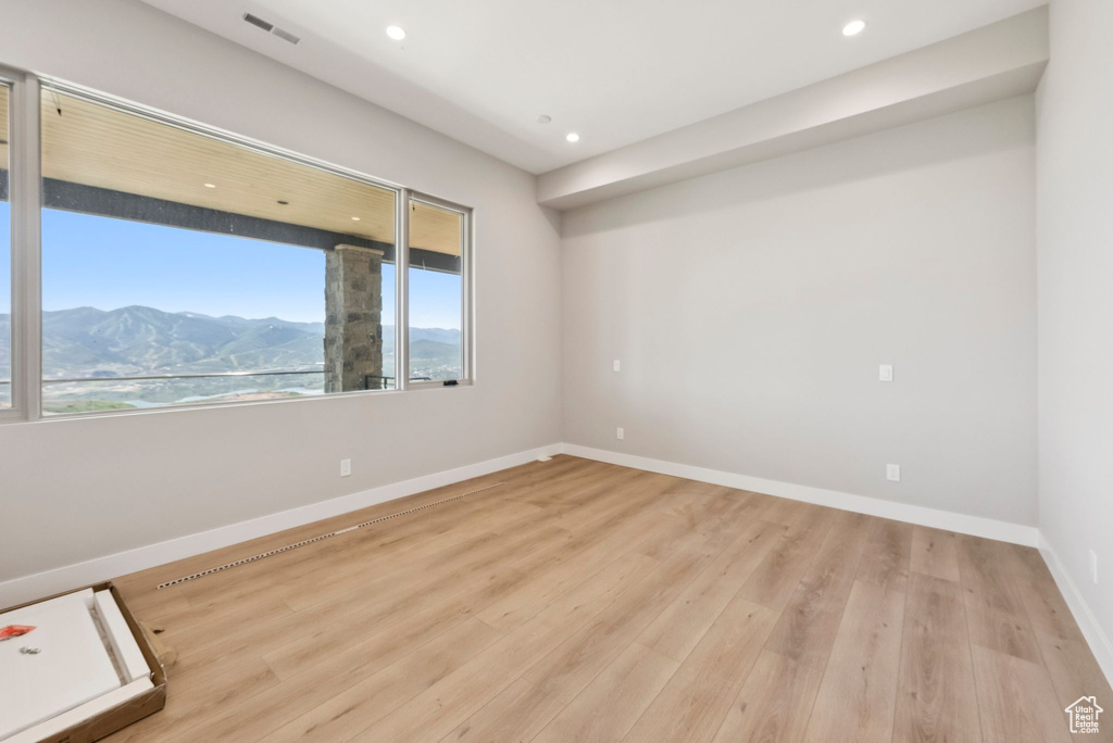 Spare room with plenty of natural light, a mountain view, wood finished floors, and recessed lighting