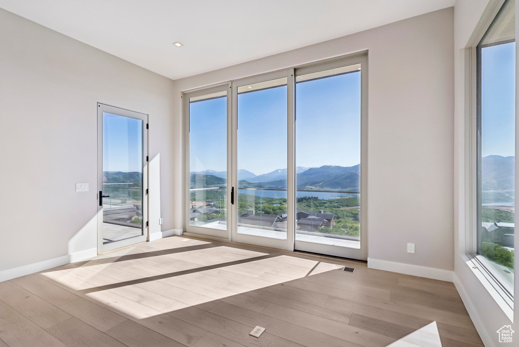 Empty room with a mountain view, wood finished floors, and healthy amount of natural light