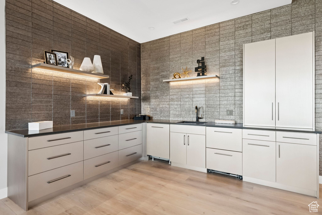 Kitchen featuring open shelves, decorative backsplash, dark countertops, light wood finished floors, and white cabinets
