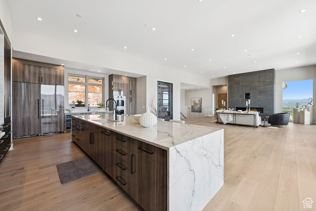 Kitchen with modern cabinets, a large island with sink, light wood-style floors, plenty of natural light, and recessed lighting