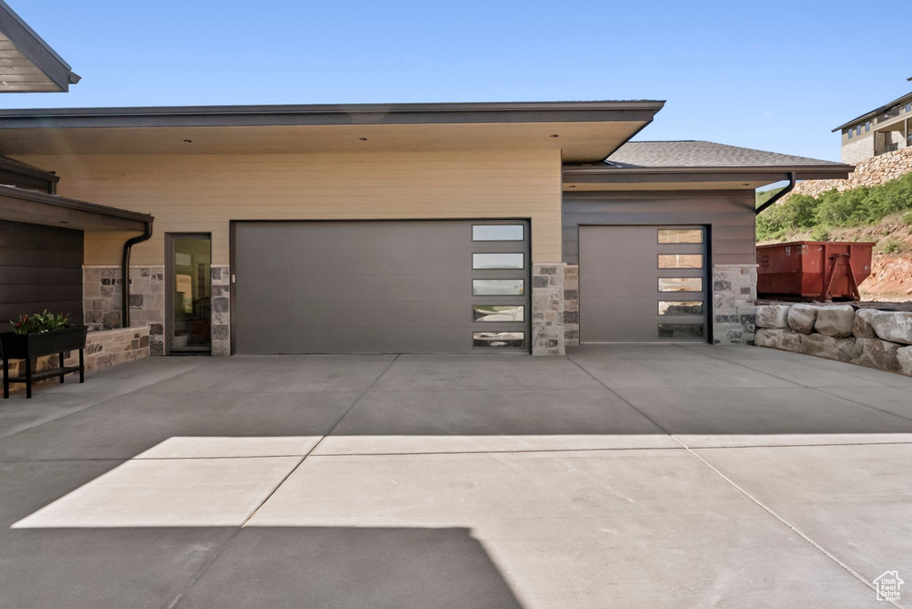 View of front of property with driveway, stone siding, and a garage