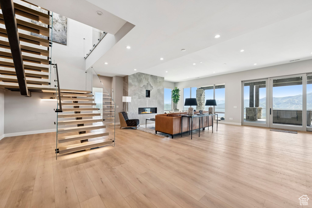 Living room featuring light wood finished floors, stairs, recessed lighting, and a high end fireplace