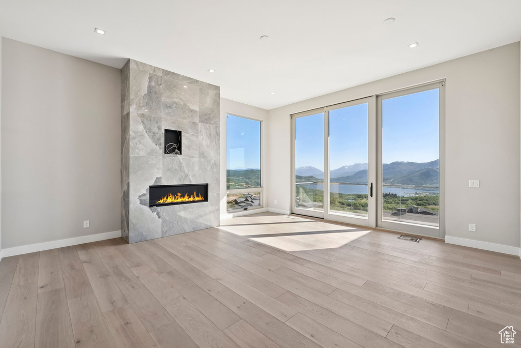 Unfurnished living room featuring a mountain view, wood finished floors, a high end fireplace, and recessed lighting