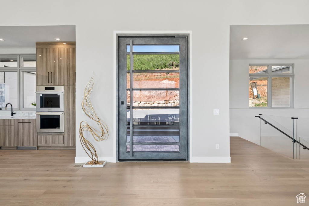 Kitchen featuring modern cabinets, light wood-style floors, brown cabinets, double oven, and recessed lighting