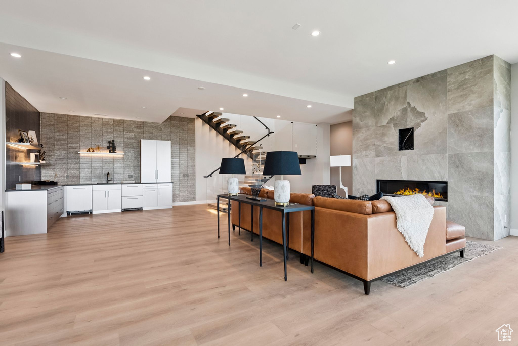 Living room with recessed lighting, light wood-type flooring, stairway, and a tiled fireplace
