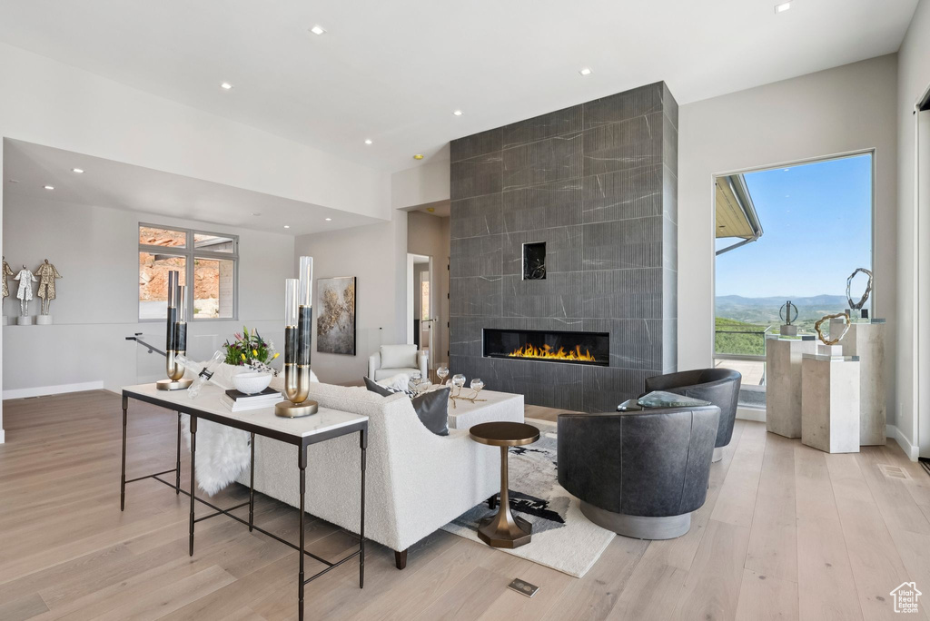 Living room with light wood-style flooring, a tile fireplace, plenty of natural light, recessed lighting, and a mountain view