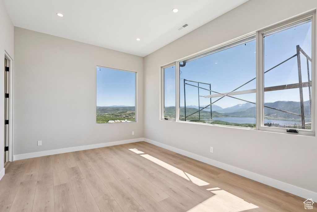 Unfurnished room with light wood-style floors, recessed lighting, and a water and mountain view