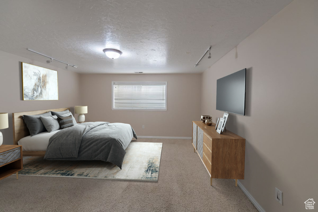 Bedroom featuring carpet floors, a textured ceiling, and track lighting