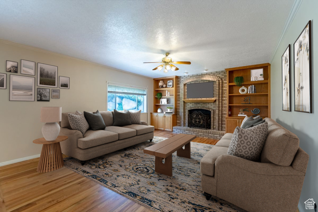 Living room with a textured ceiling, built in shelves, ceiling fan, a brick fireplace, and hardwood / wood-style floors