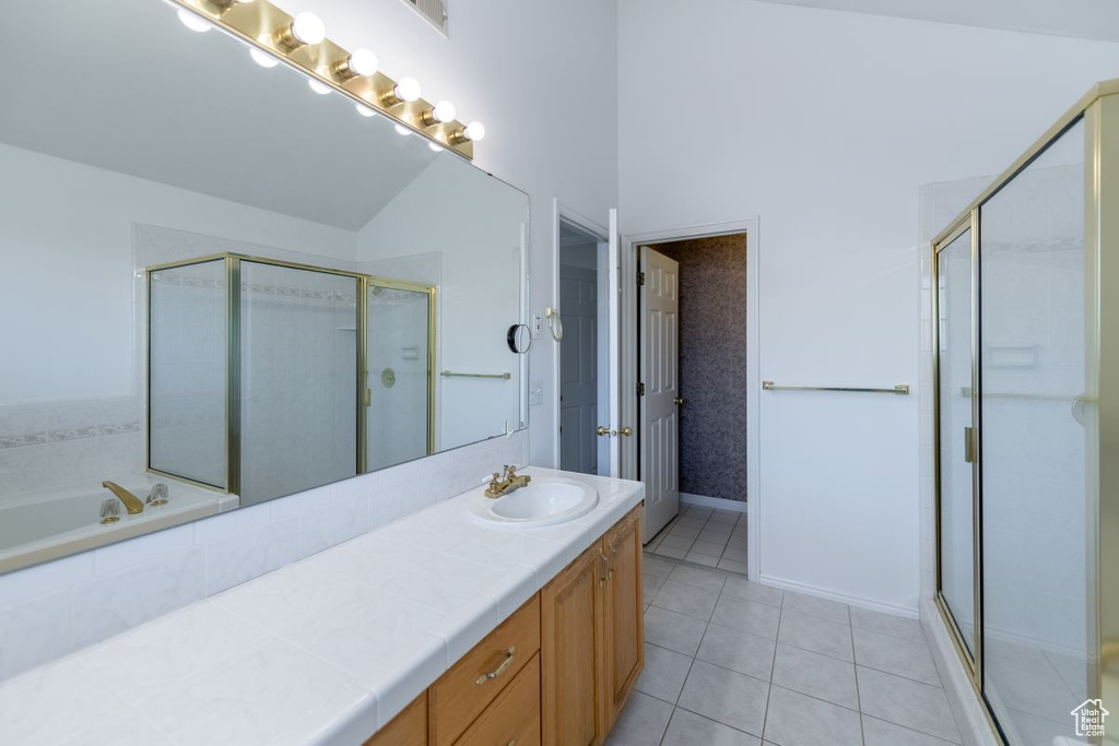 Bathroom featuring tile patterned flooring, lofted ceiling, separate shower and tub, and vanity