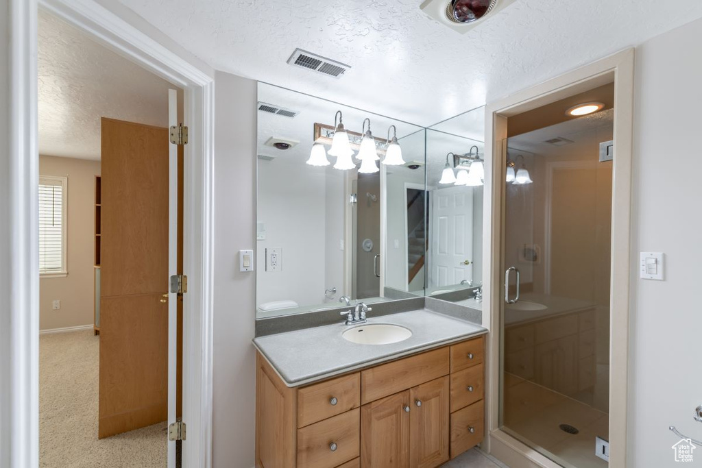 Bathroom with a shower with door, vanity, and a textured ceiling