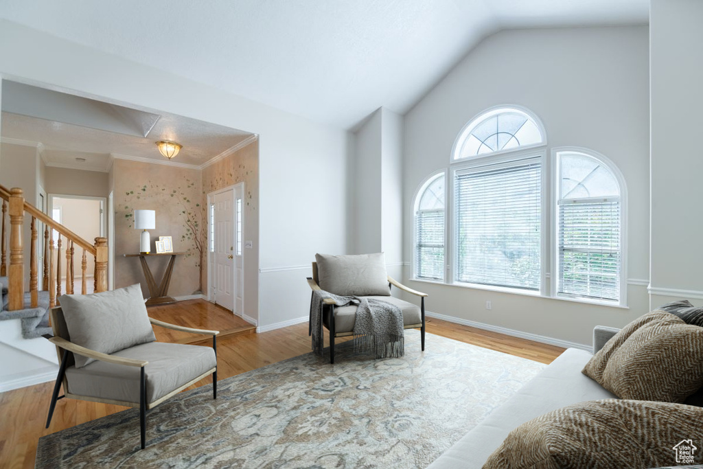 Interior space featuring lofted ceiling, wood-type flooring, and crown molding