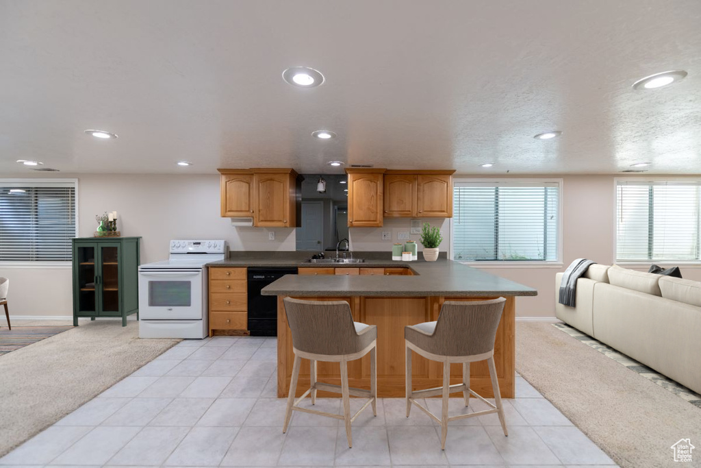 Kitchen with a breakfast bar, light tile patterned floors, white electric range oven, dishwasher, and sink