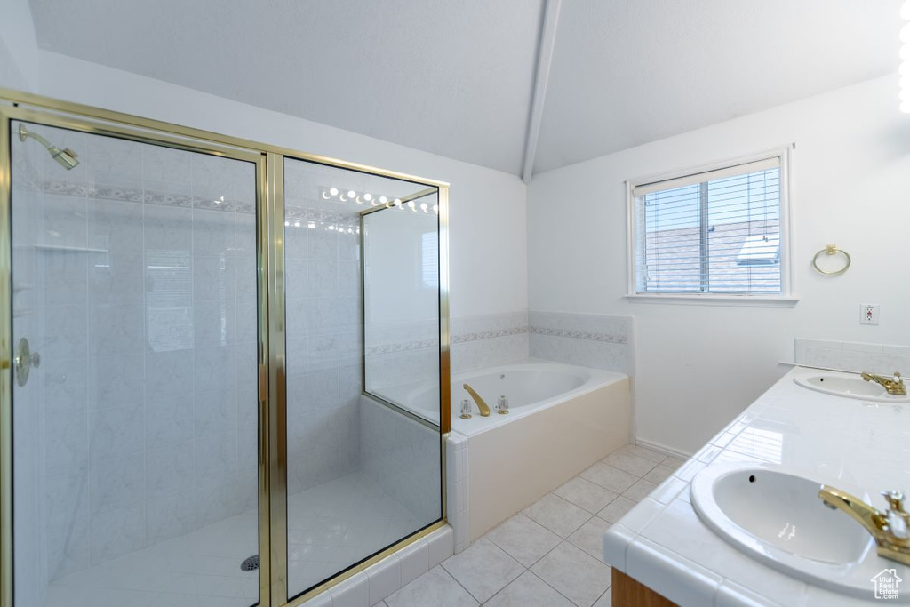 Bathroom with tile patterned floors, dual vanity, separate shower and tub, and vaulted ceiling