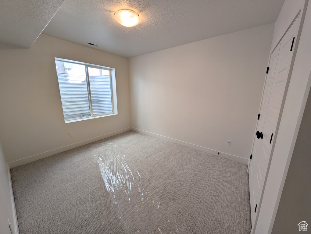 Carpeted spare room featuring a textured ceiling