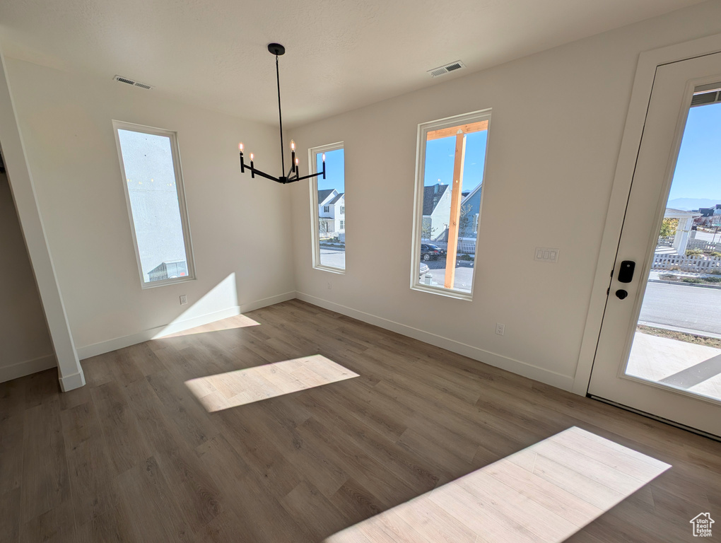 Unfurnished dining area featuring dark wood-type flooring and a chandelier