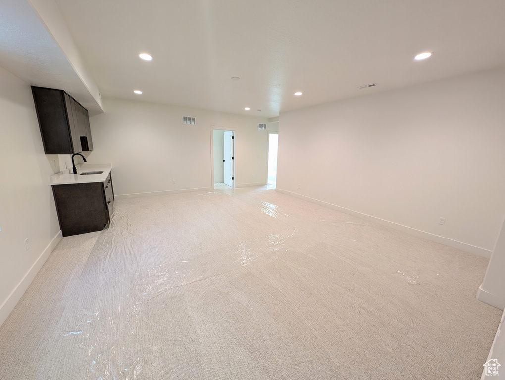 Unfurnished living room with light carpet and sink