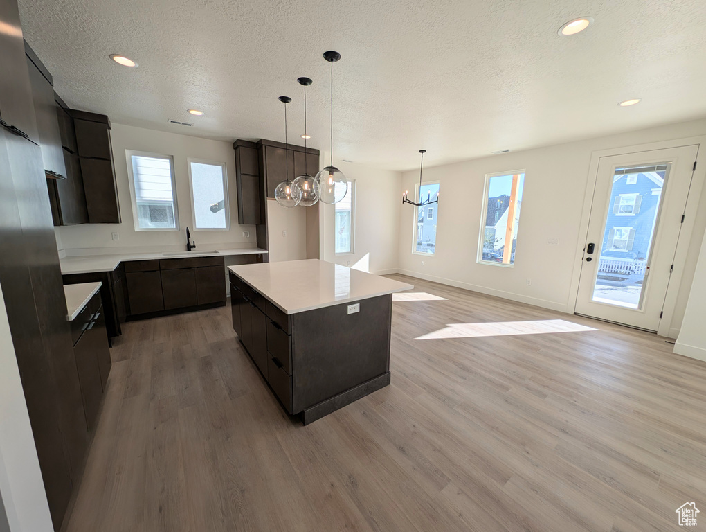 Kitchen featuring sink, light hardwood / wood-style floors, a center island, and decorative light fixtures