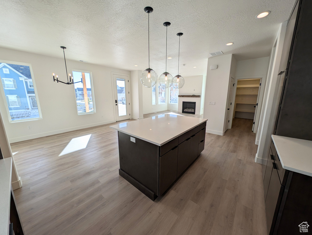 Kitchen with a textured ceiling, a center island, light wood-type flooring, and a wealth of natural light