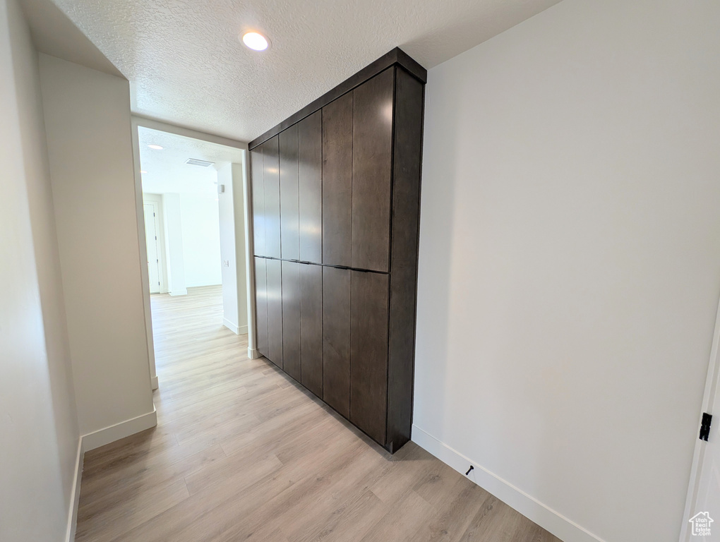 Hallway featuring a textured ceiling and light wood-type flooring