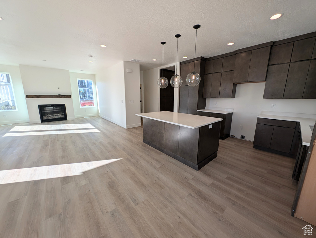 Kitchen featuring a kitchen island, hanging light fixtures, a textured ceiling, and light wood-type flooring