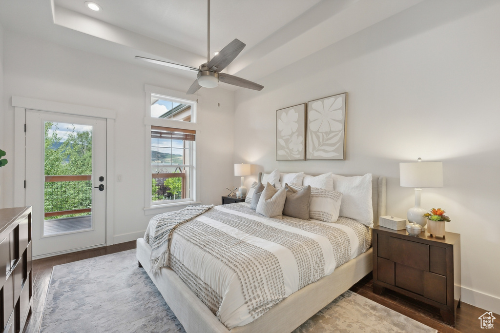 Bedroom with ceiling fan, access to outside, dark hardwood / wood-style flooring, and multiple windows