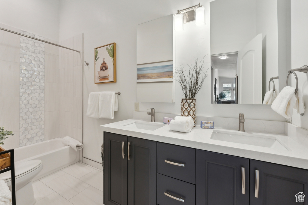 Full bathroom with tile patterned flooring, tiled shower / bath combo, toilet, and dual bowl vanity