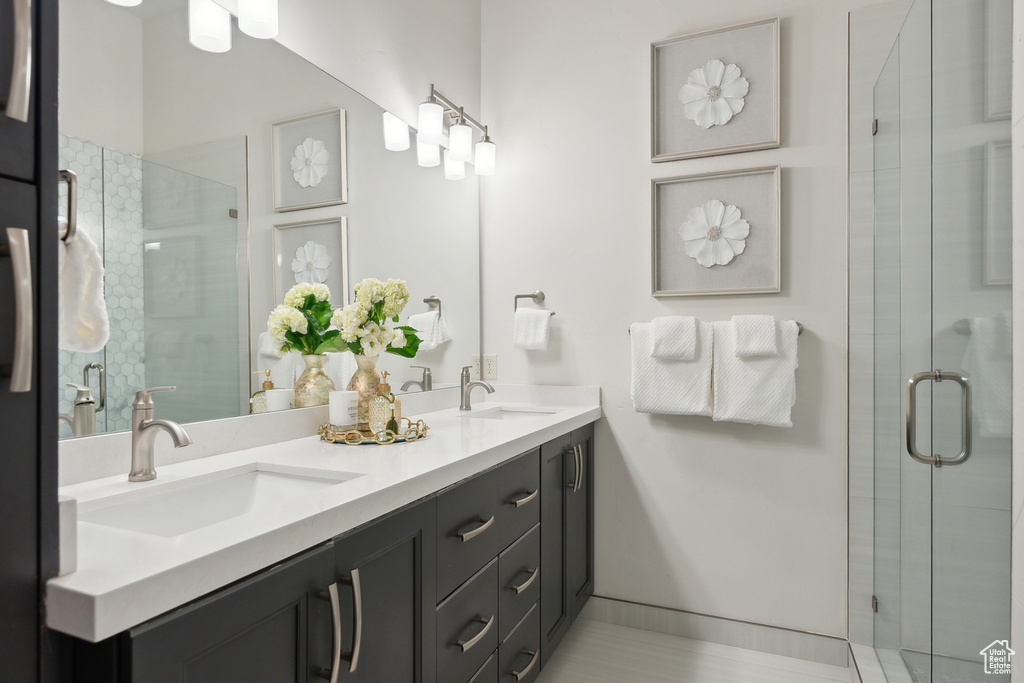 Bathroom featuring tile patterned floors, double sink vanity, and an enclosed shower