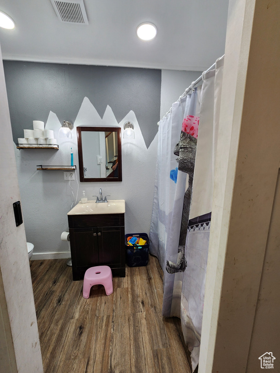 Bathroom featuring hardwood / wood-style flooring, toilet, and vanity