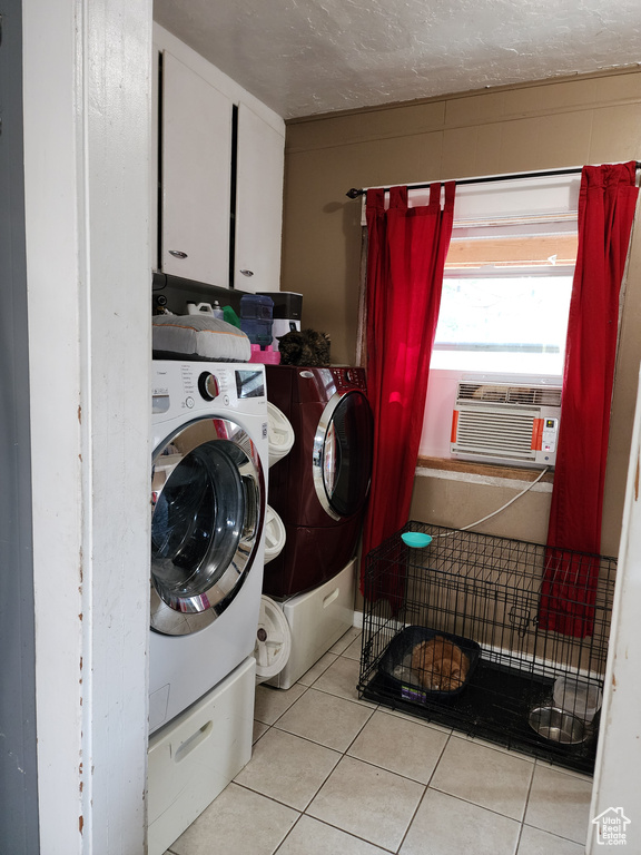 Washroom featuring cooling unit, washing machine and dryer, and light tile patterned floors