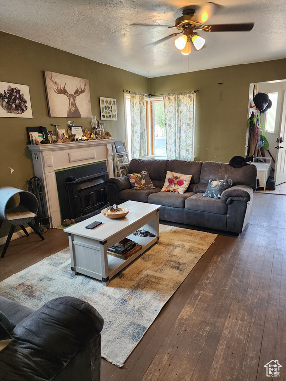 Living room featuring a textured ceiling, hardwood / wood-style flooring, and ceiling fan