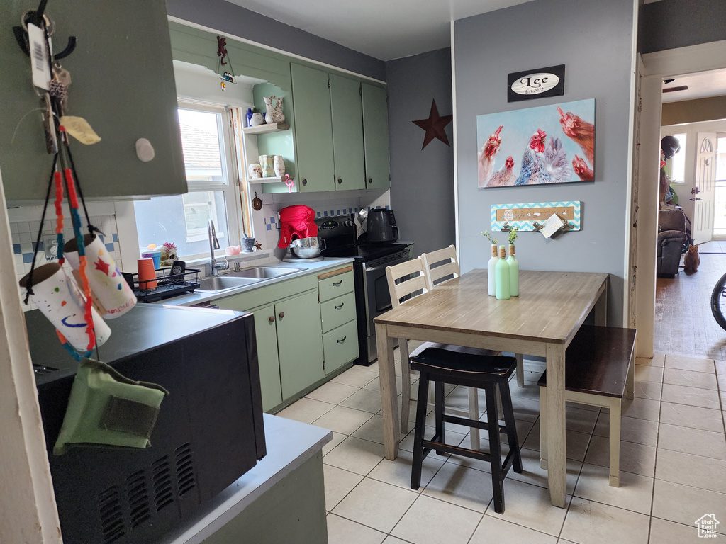 Kitchen with electric range, sink, light tile patterned flooring, and green cabinetry