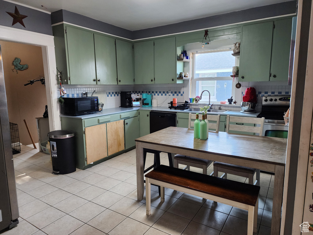 Kitchen featuring black appliances, sink, backsplash, light tile patterned floors, and green cabinets