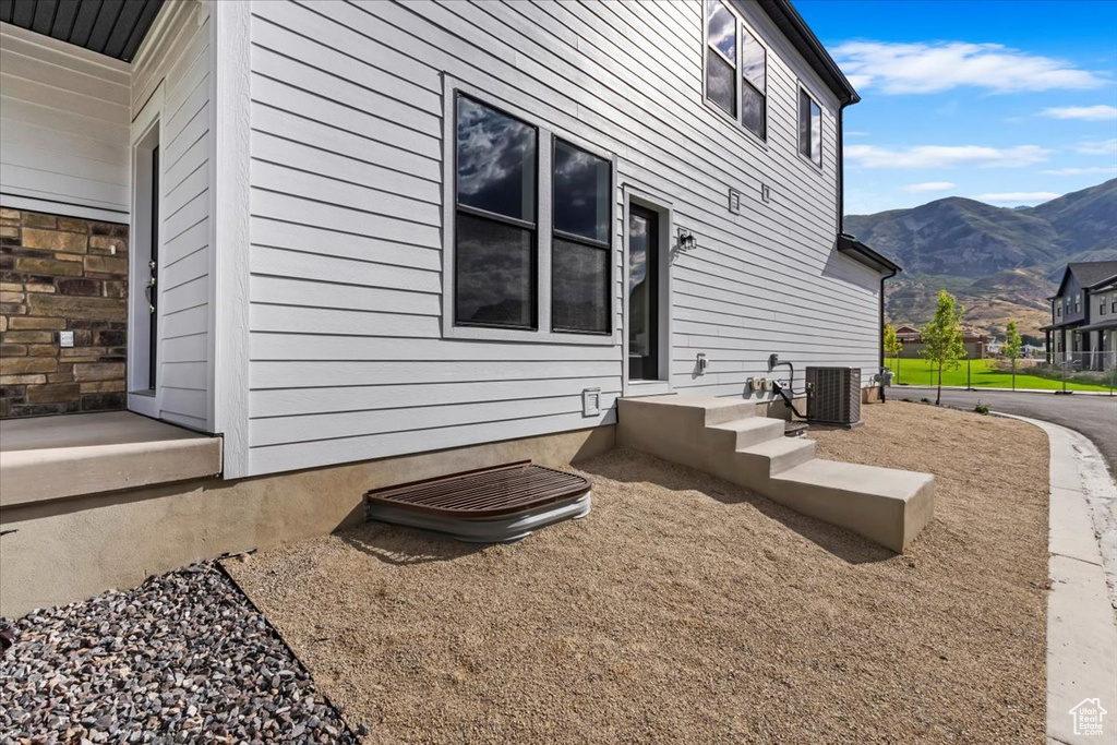 View of side of home featuring a mountain view and central AC