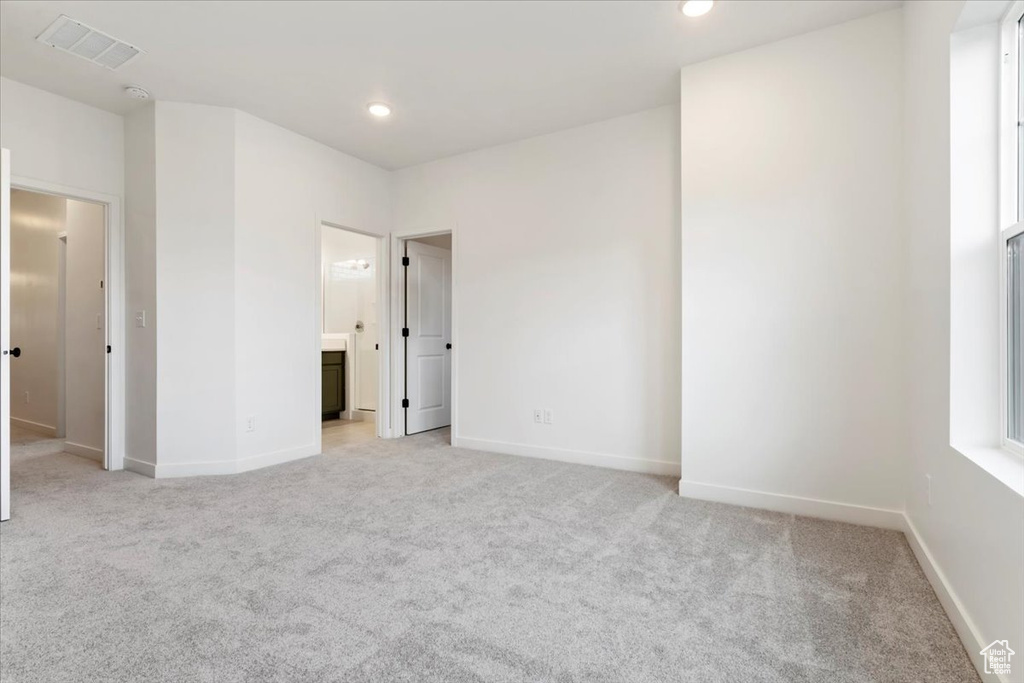 Unfurnished bedroom featuring connected bathroom and light carpet