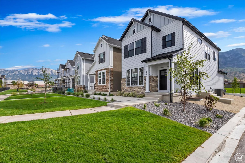 View of front of house featuring central air condition unit, a mountain view, and a front yard