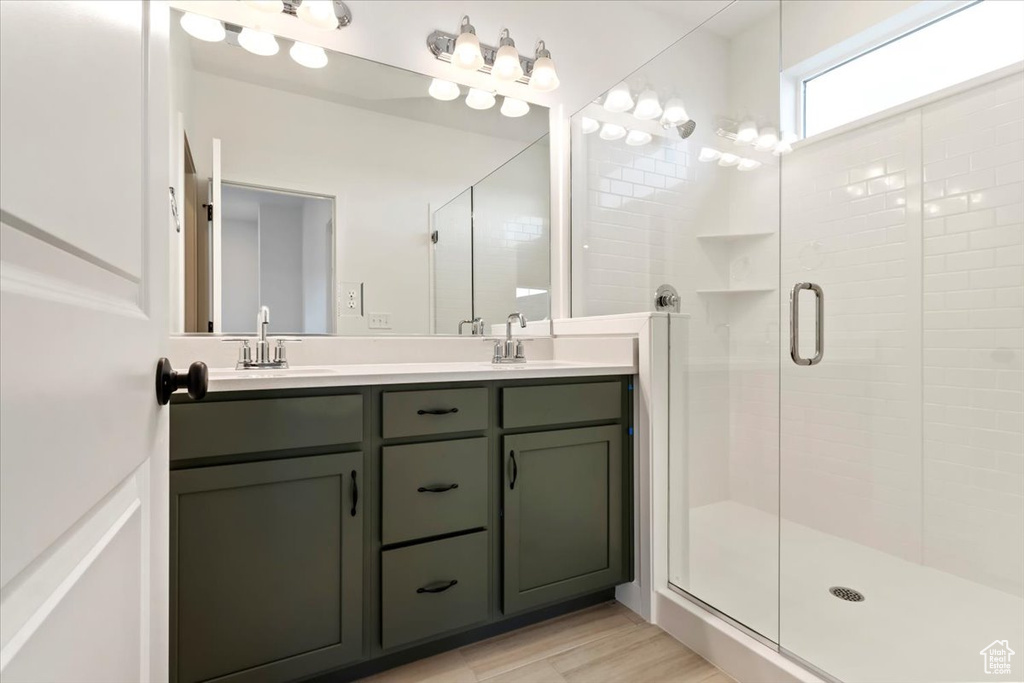 Bathroom with vanity, hardwood / wood-style floors, and a shower with shower door