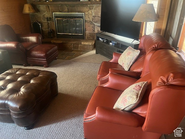 Carpeted living room featuring a stone fireplace