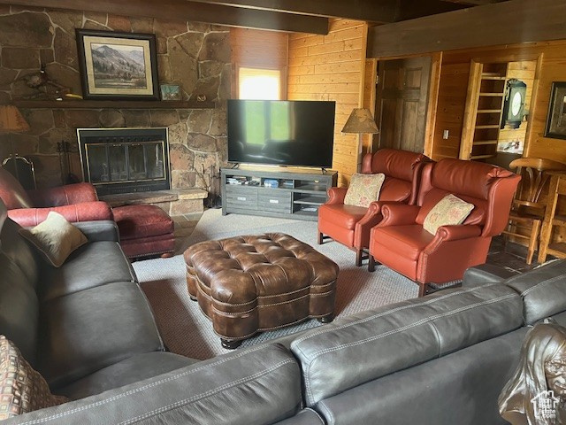 Carpeted living area with wooden walls and a stone fireplace
