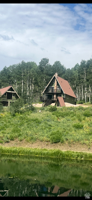 Back of house with a water view, a forest view, and a metal roof