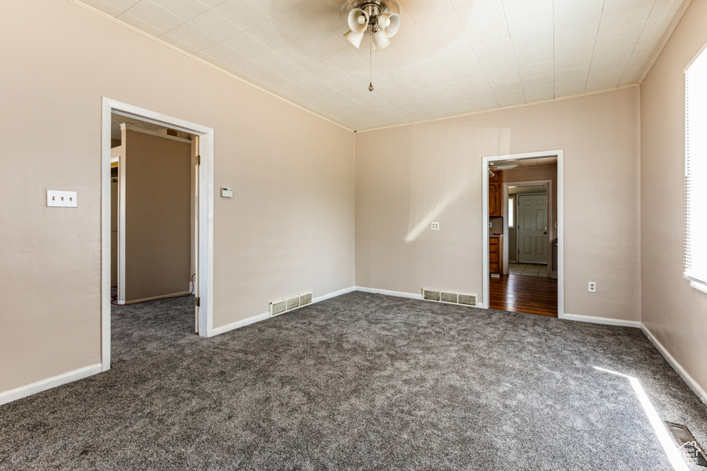 Carpeted spare room featuring ceiling fan and crown molding