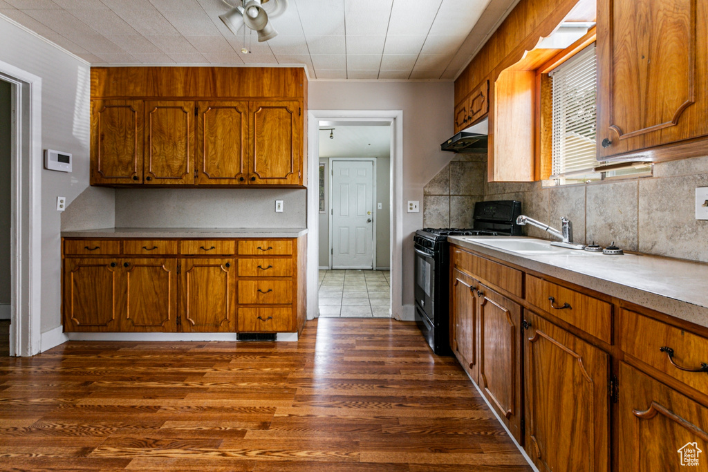 Kitchen with sink, black range oven, tasteful backsplash, and dark hardwood / wood-style floors