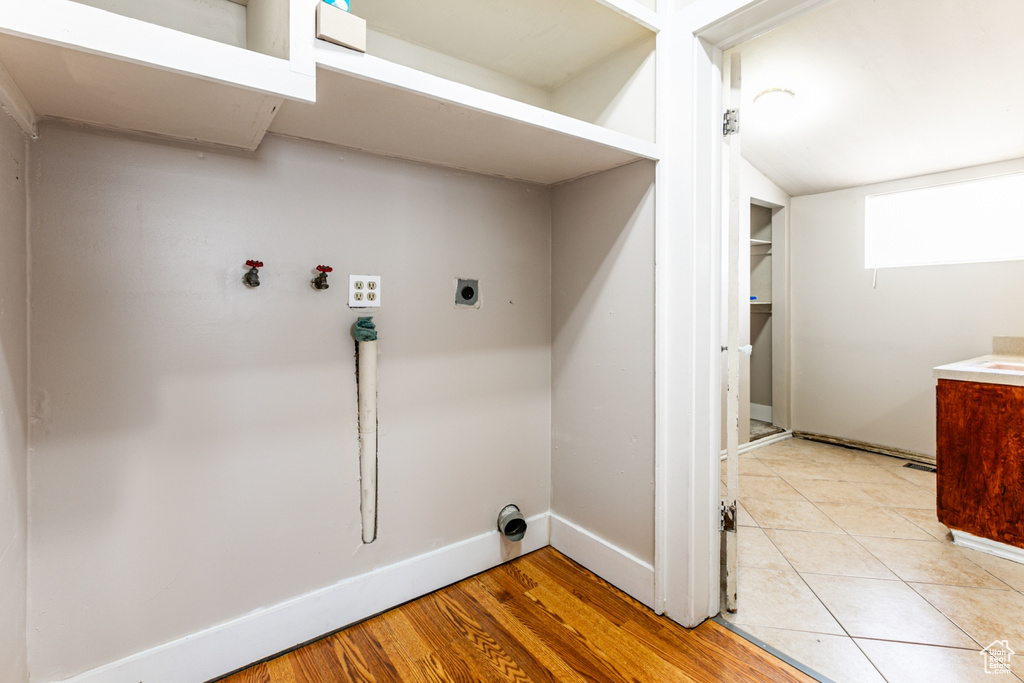 Clothes washing area with washer hookup, electric dryer hookup, and light wood-type flooring