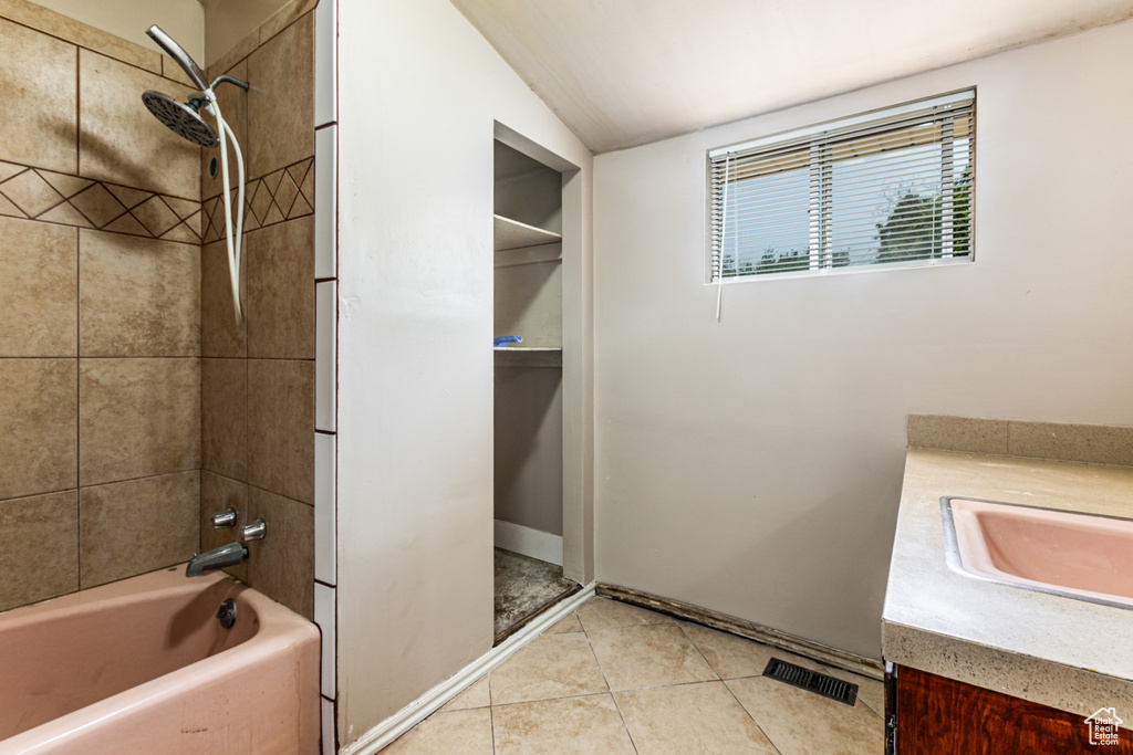 Bathroom featuring vanity, tile patterned flooring, tiled shower / bath combo, and lofted ceiling