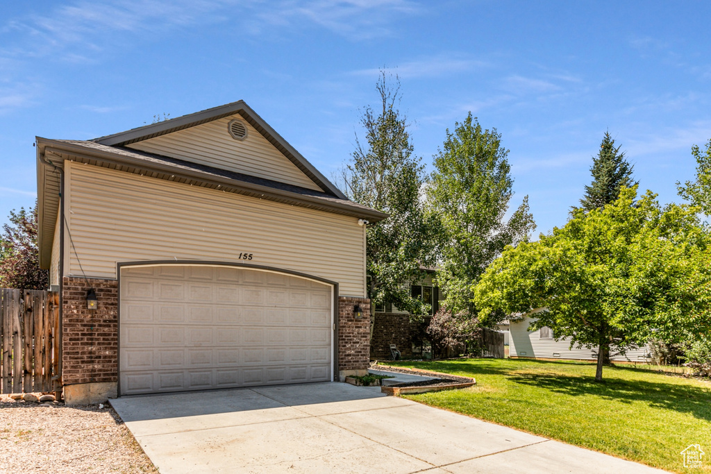 View of side of property with a garage and a lawn