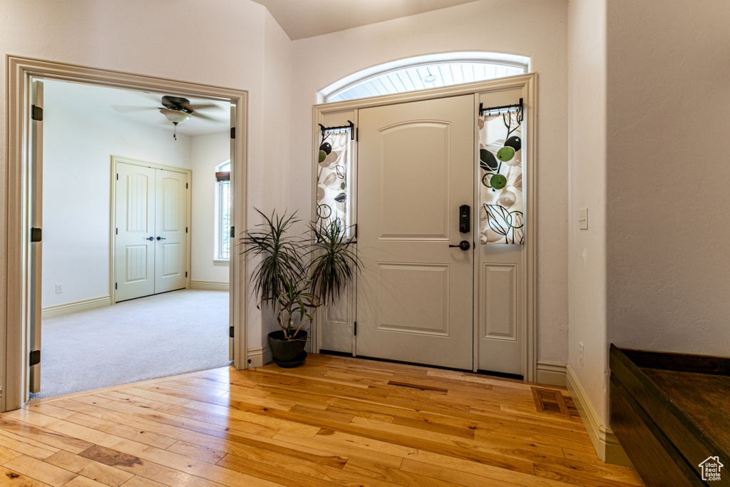 Foyer with light colored carpet, a wealth of natural light, and ceiling fan