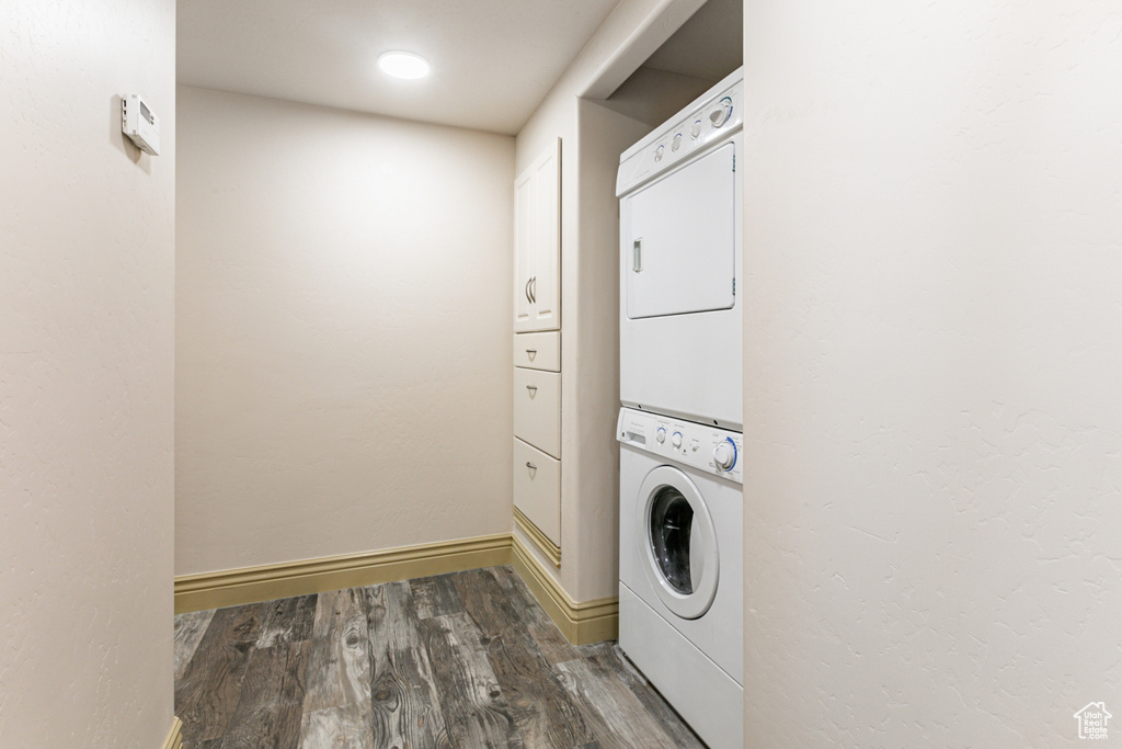 Washroom featuring stacked washer / dryer and dark hardwood / wood-style flooring