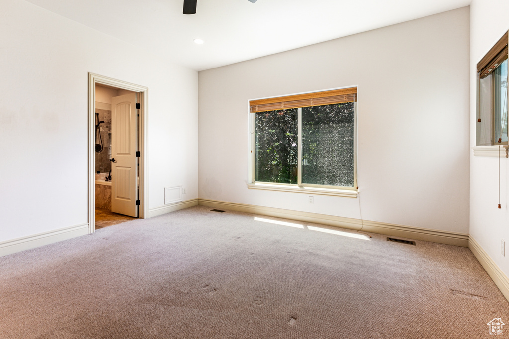 Unfurnished bedroom with ensuite bathroom, ceiling fan, and light colored carpet