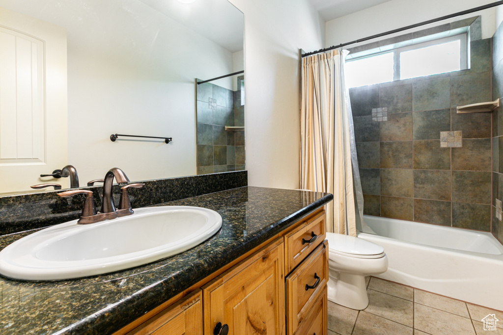 Full bathroom with tile patterned floors, shower / bath combination with curtain, toilet, and vanity